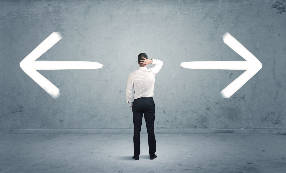 A businessman in doubt, having to shoose between two different choices indicated by arrows pointing in opposite direction concept