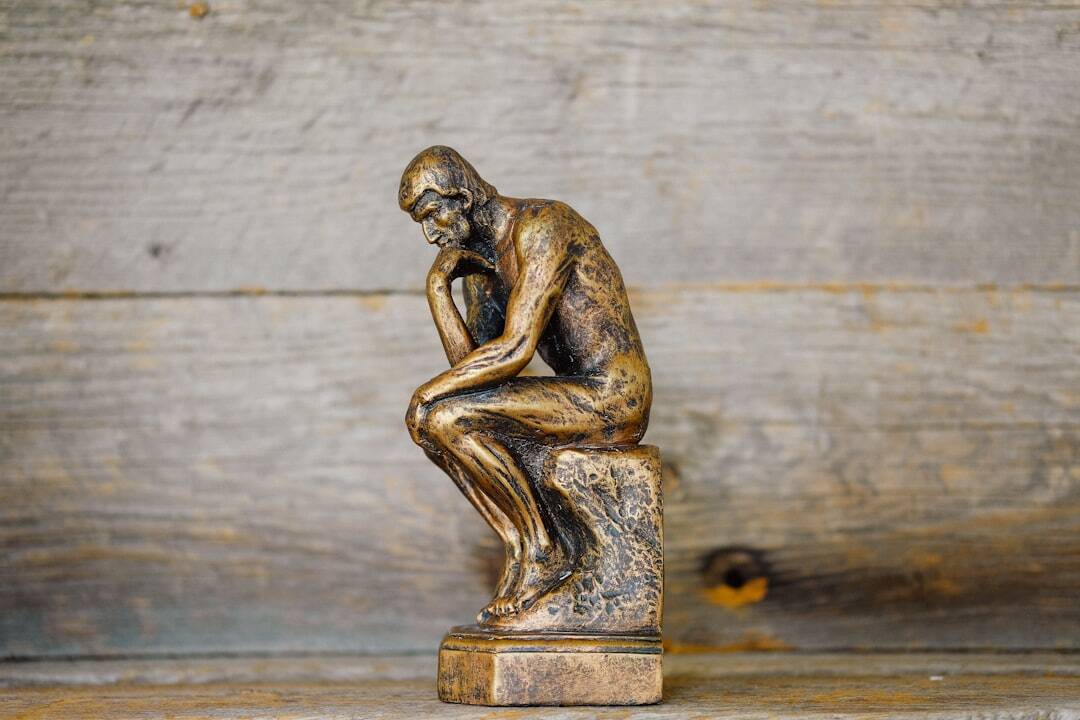 bronze sculpture of the thinker man with head in hand