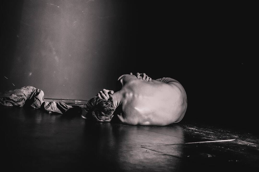 black and white photo of someone in fetal position no shirt with arms around themselves back facing us