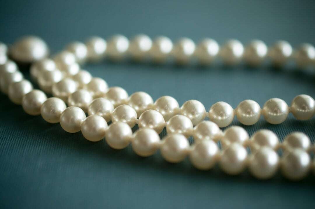 white strand of pearls on a bluish green table