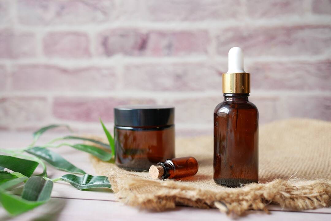 clear brown jars and bottles on a wooden tray with greenery and brick wall background