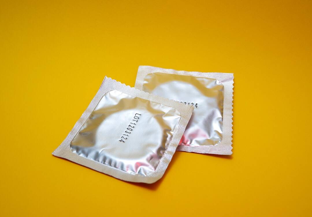 picture of two silver wrapped condoms on a yellow background