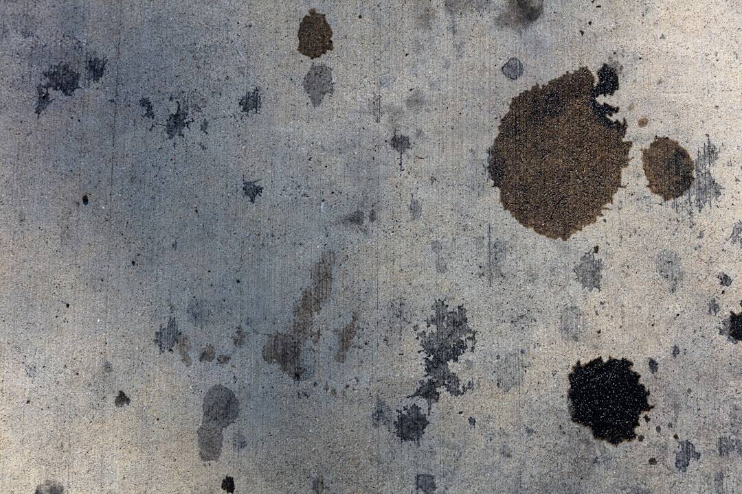 beige back ground with circular black ink stains of different sizes splattered on it