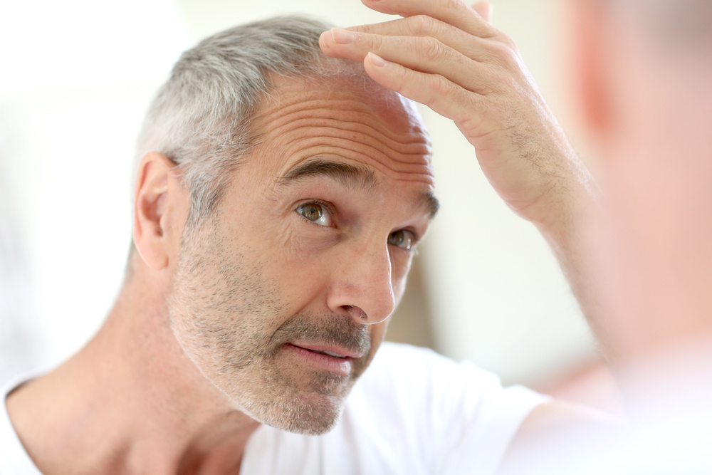 man with grey hair evaluating his hair in the mirror