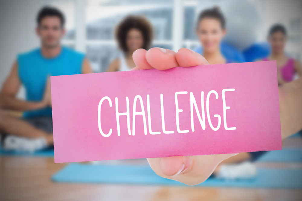 Woman holding pink card saying challenge against yoga class in gym
