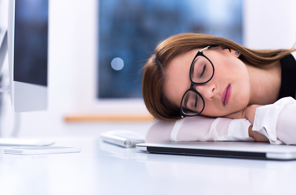 Young businesswoman in glasses sleeping at her workplace